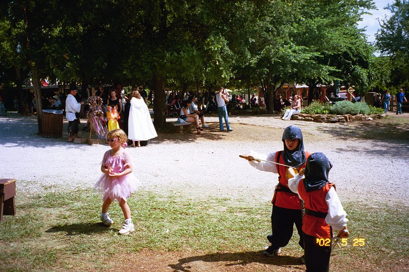 Jacob and David sword fighting while Sara VanNewkirk is ignoring them